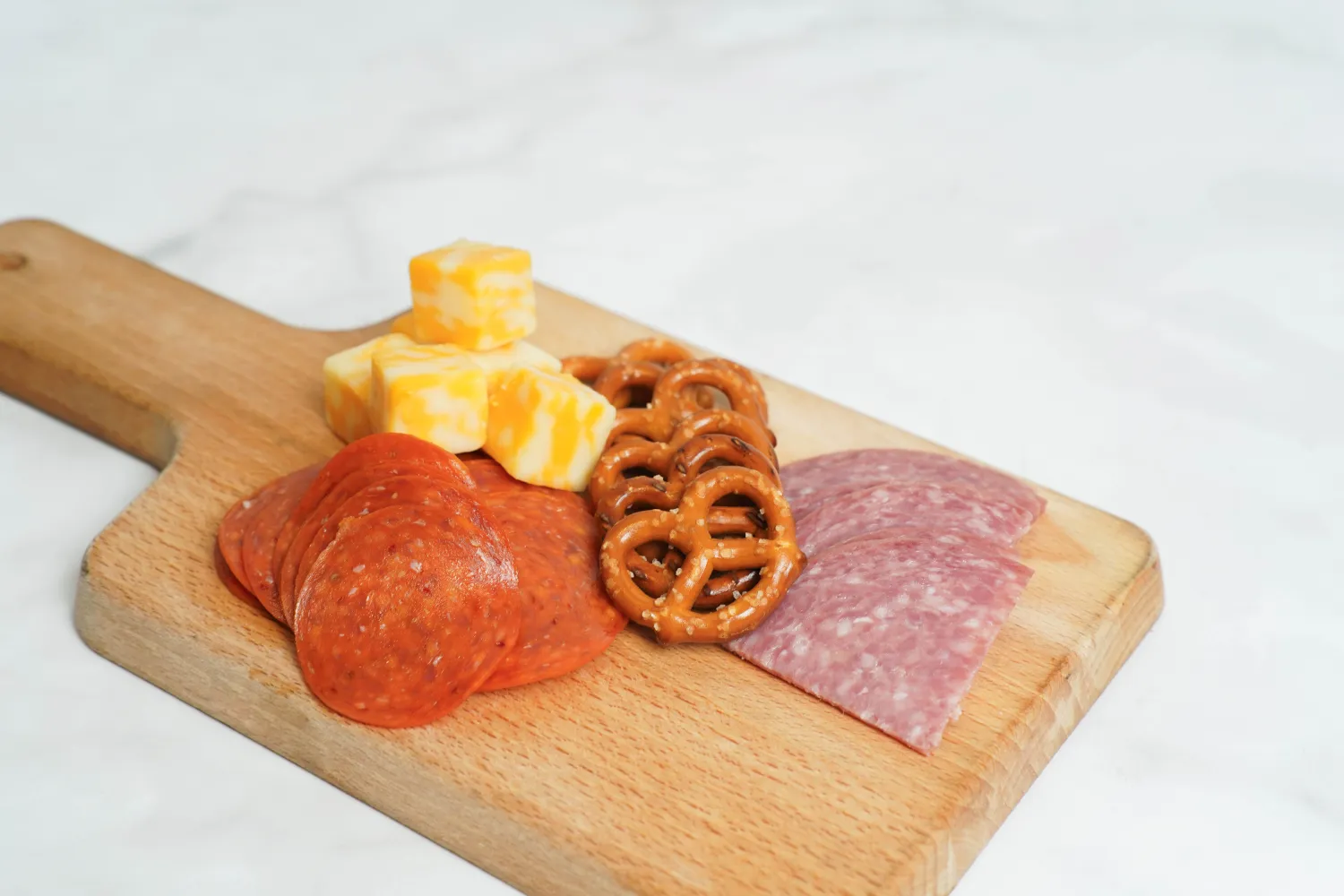 Small charcuterie board with cheese, pretzels, and cold cut meats